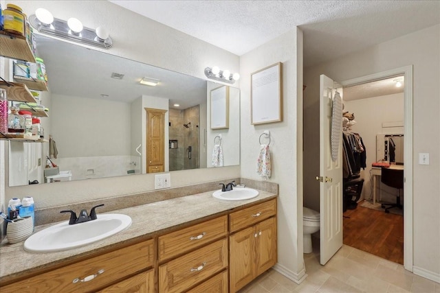 504 County Road 763 N, Buna, TX 77612 - bathroom with a stall shower, a walk in closet, double vanity, tile patterned floors, and toilet