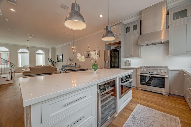 5213 Feagan St Unit H, Houston, TX 77007 - kitchen featuring appliances with stainless steel finishes, wall chimney exhaust hood, beverage cooler, light stone counters, and tasteful backsplash
