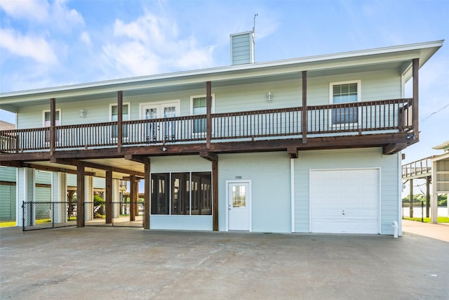 3190 Fm-2031, Matagorda, TX 77414 - back of property with an attached garage, a chimney, driveway, and a sunroom