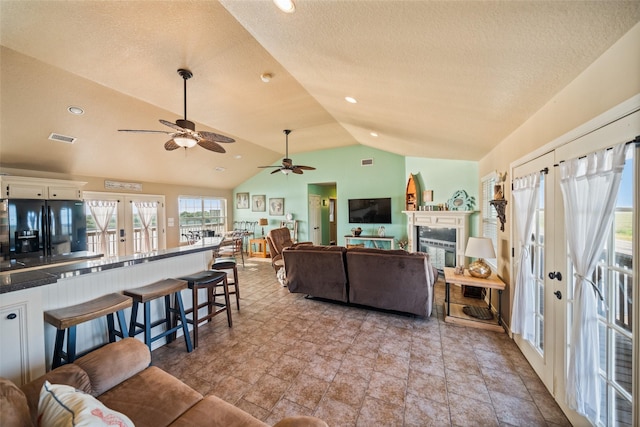 3190 Fm-2031, Matagorda, TX 77414 - living area featuring french doors, vaulted ceiling, a ceiling fan, a glass covered fireplace, and a textured ceiling