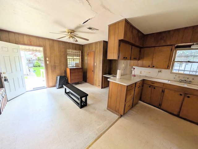 622 Gazin St, Houston, TX 77020 - kitchen featuring light countertops, wooden walls, a ceiling fan, brown cabinetry, and healthy amount of natural light