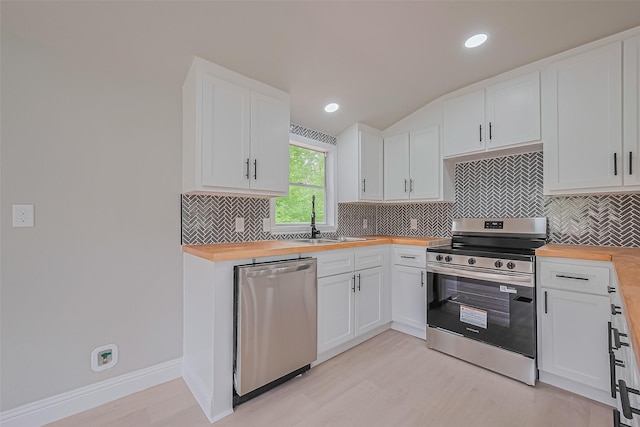 131 Holiday Blvd, Coldspring, TX 77331 - kitchen with butcher block countertops, appliances with stainless steel finishes, a sink, backsplash, and vaulted ceiling