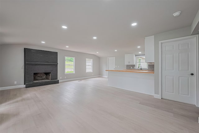 131 Holiday Blvd, Coldspring, TX 77331 - unfurnished living room featuring light wood-style flooring, recessed lighting, baseboards, a fireplace, and a sink