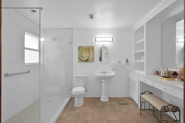 9141 Oak Arbor Dr, Conroe, TX 77384 - bathroom featuring a tile shower, a textured ceiling, toilet, and tile patterned floors