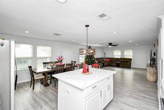 20695 Liberty St, New Caney, TX 77357 - kitchen with freestanding refrigerator, healthy amount of natural light, a kitchen island, light wood finished floors, and a textured ceiling