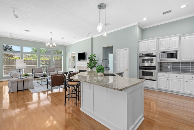 1107 Walden Hill Ct, Houston, TX 77077 - kitchen featuring stainless steel appliances, a sink, open floor plan, white cabinets, and light wood-style flooring
