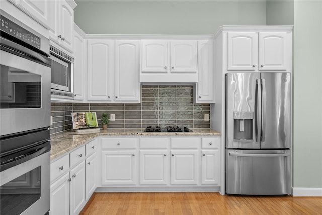 1107 Walden Hill Ct, Houston, TX 77077 - kitchen featuring stainless steel appliances, backsplash, light stone countertops, white cabinets, and light wood-style floors