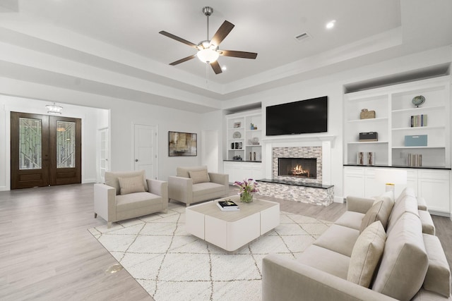 28200 E Stallion Ln, Waller, TX 77484 - living area with a raised ceiling, light wood-style floors, a ceiling fan, a stone fireplace, and recessed lighting