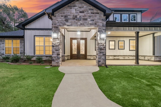 28200 E Stallion Ln, Waller, TX 77484 - view of exterior entry featuring french doors, stone siding, board and batten siding, and a lawn