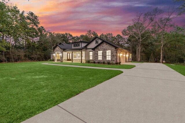 28200 E Stallion Ln, Waller, TX 77484 - view of front facade with stone siding, concrete driveway, a front yard, an attached garage, and board and batten siding
