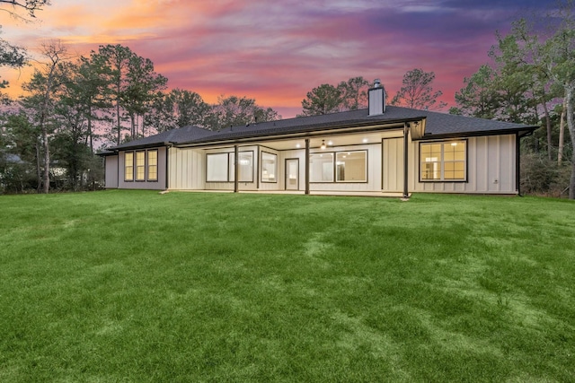 28200 E Stallion Ln, Waller, TX 77484 - back of house at dusk with a chimney, board and batten siding, and a lawn