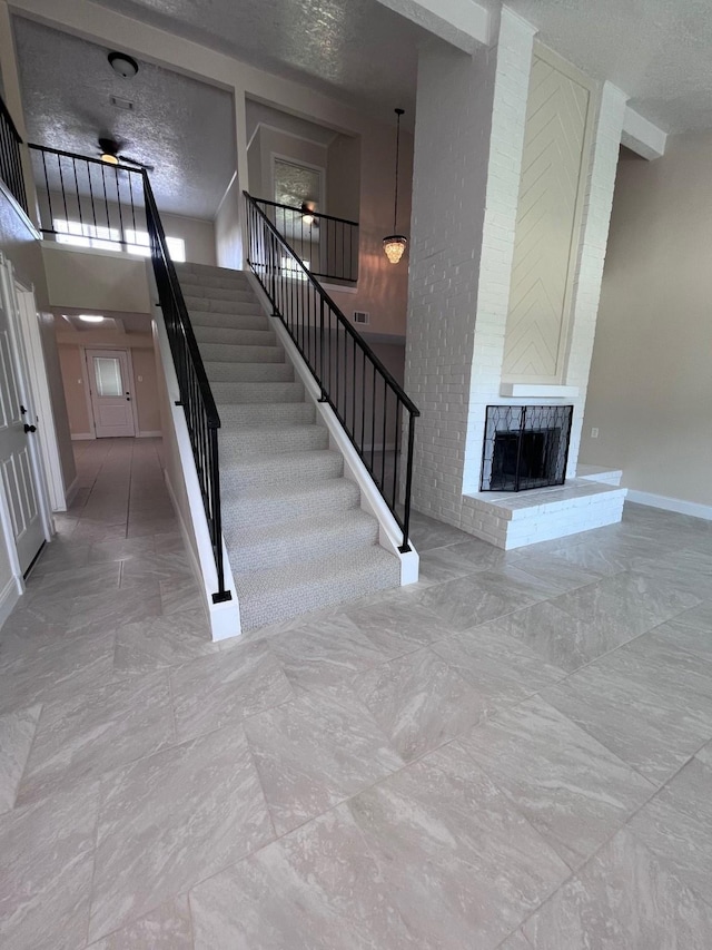8330 Blue Quail Dr, Houston, TX 77489 - stairway with a fireplace, a textured ceiling, marble finish flooring, and baseboards