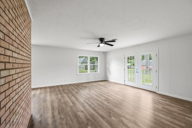606 Clayton St, Tomball, TX 77375 - unfurnished room with wood finished floors, plenty of natural light, ceiling fan, baseboards, and brick wall