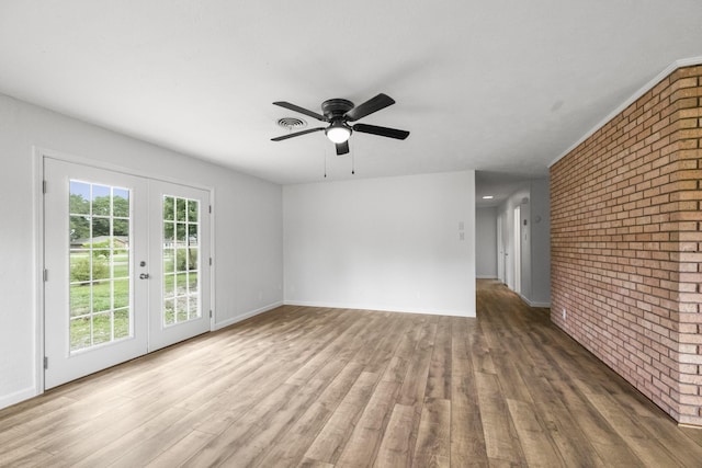 606 Clayton St, Tomball, TX 77375 - empty room featuring brick wall, french doors, wood finished floors, a ceiling fan, and baseboards