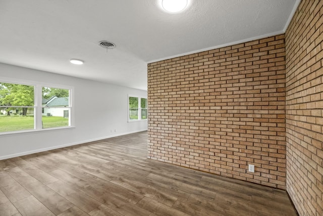 606 Clayton St, Tomball, TX 77375 - unfurnished room featuring brick wall and dark wood-type flooring