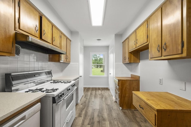 606 Clayton St, Tomball, TX 77375 - kitchen featuring white appliances, under cabinet range hood, wood finished floors, tasteful backsplash, and brown cabinetry