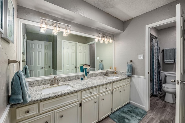 3706 Autumn Ln, Baytown, TX 77521 - full bath with a textured ceiling, double vanity, wood finished floors, toilet, and a textured wall