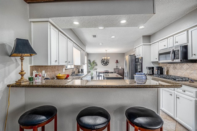 3706 Autumn Ln, Baytown, TX 77521 - kitchen featuring appliances with stainless steel finishes, a textured ceiling, tasteful backsplash, a sink, and white cabinetry