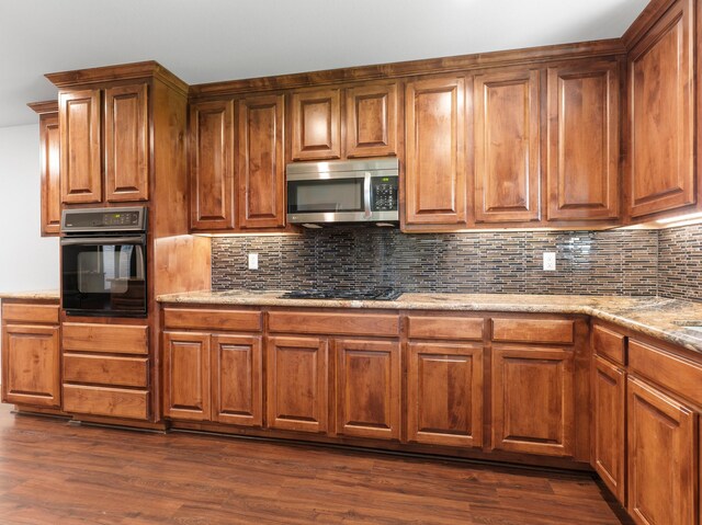 14624 Dove Ln, Needville, TX 77461 - kitchen with black appliances, tasteful backsplash, brown cabinetry, and dark wood-type flooring