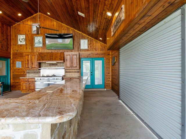 14624 Dove Ln, Needville, TX 77461 - kitchen featuring wooden walls, brown cabinetry, french doors, unfinished concrete floors, and high end stove