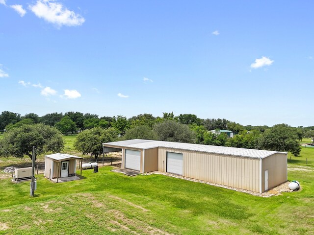 14624 Dove Ln, Needville, TX 77461 - view of green lawn with a garage, an outdoor structure, an outbuilding, and view of wooded area
