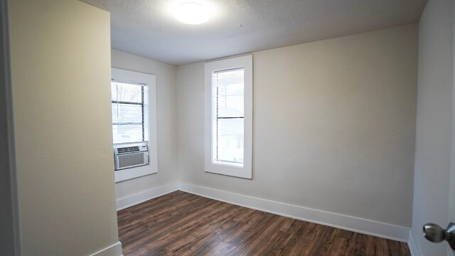 1126 Ryon St, Houston, TX 77009 - empty room featuring baseboards, dark wood-type flooring, cooling unit, and plenty of natural light