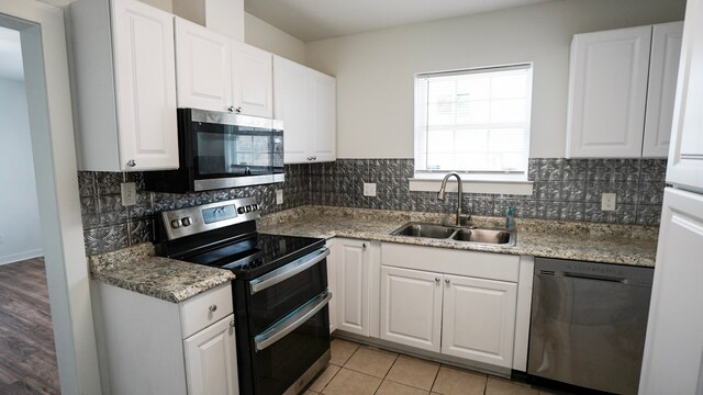 1126 Ryon St, Houston, TX 77009 - kitchen with stainless steel appliances, a sink, white cabinets, and decorative backsplash