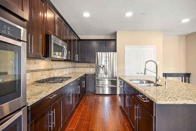 4911 Lattimore Creek Dr, Houston, TX 77084 - kitchen featuring appliances with stainless steel finishes, a sink, dark wood finished floors, light stone countertops, and recessed lighting
