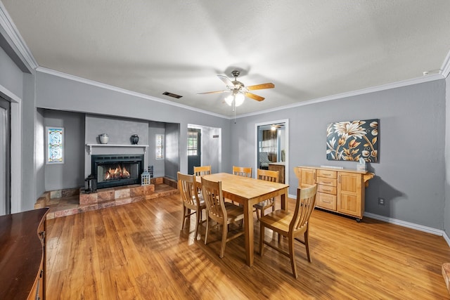 1307 Hillcrest Dr, Granite Shoals, TX 78654 - dining space with light wood-type flooring, a warm lit fireplace, plenty of natural light, and ornamental molding