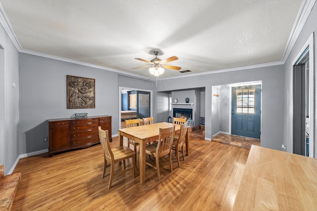 1307 Hillcrest Dr, Granite Shoals, TX 78654 - dining space with light wood-style floors, a fireplace, ceiling fan, crown molding, and baseboards