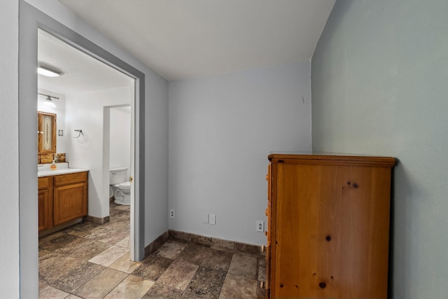 1307 Hillcrest Dr, Granite Shoals, TX 78654 - unfurnished bedroom with stone finish flooring, baseboards, ensuite bath, and a sink