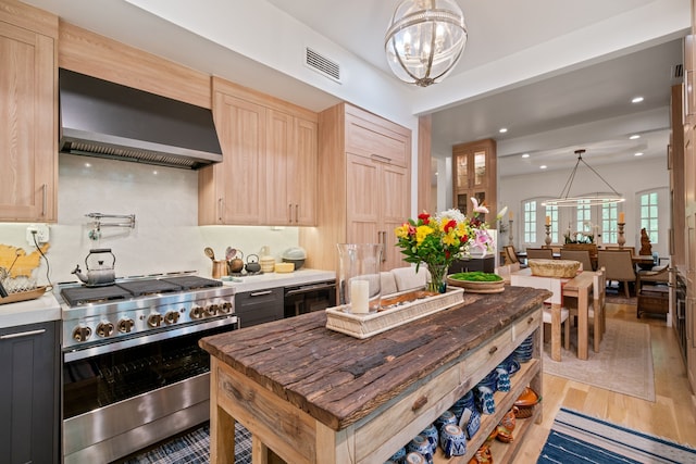 10 S Briar Hollow Ln Unit 30, Houston, TX 77027 - kitchen with high end stainless steel range oven, wall chimney exhaust hood, light brown cabinetry, light wood-style flooring, and a chandelier