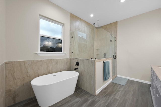 40380 Mostyn Dr, Magnolia, TX 77354 - bathroom with a shower stall, vanity, a freestanding tub, wood finished floors, and tile walls