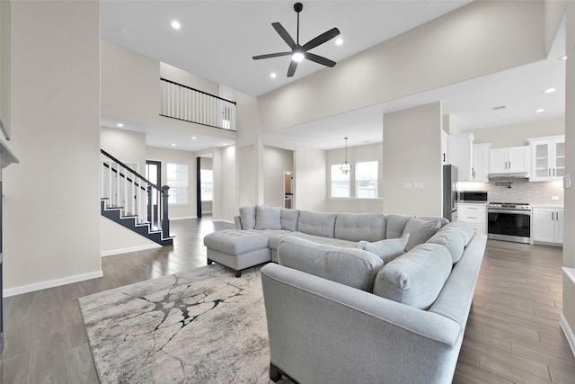 40380 Mostyn Dr, Magnolia, TX 77354 - living room with light wood-style floors, a ceiling fan, healthy amount of natural light, stairway, and a towering ceiling