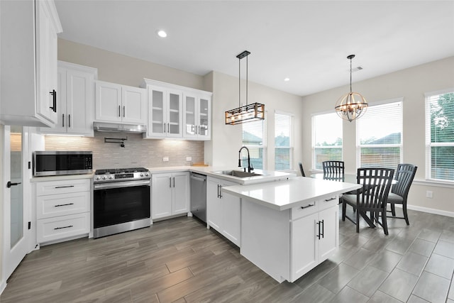 40380 Mostyn Dr, Magnolia, TX 77354 - kitchen with stainless steel appliances, a peninsula, decorative backsplash, light countertops, and a sink