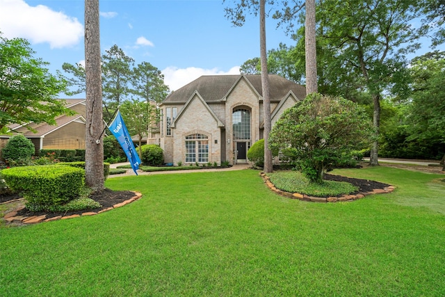 46 Rolling Links Ct, The Woodlands, TX 77380 - french country style house featuring brick siding, a front lawn, and roof with shingles