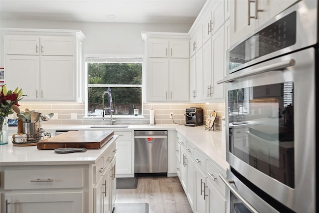 46 Rolling Links Ct, The Woodlands, TX 77380 - kitchen with appliances with stainless steel finishes, a sink, tasteful backsplash, light countertops, and white cabinetry