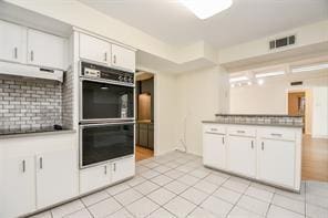 5502 Dumfries Dr, Houston, TX 77096 - kitchen with white cabinetry, light tile patterned floors, and under cabinet range hood