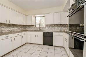 5502 Dumfries Dr, Houston, TX 77096 - kitchen with black appliances, white cabinets, decorative backsplash, a sink, and light countertops