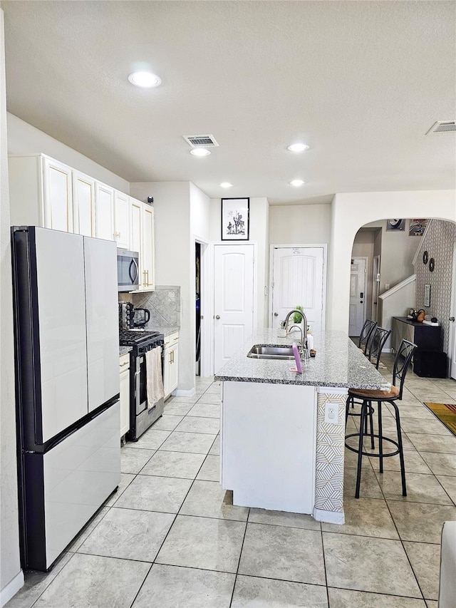 3519 Rossini Dr, Katy, TX 77493 - kitchen with stainless steel appliances, a sink, arched walkways, light stone counters, and a breakfast bar