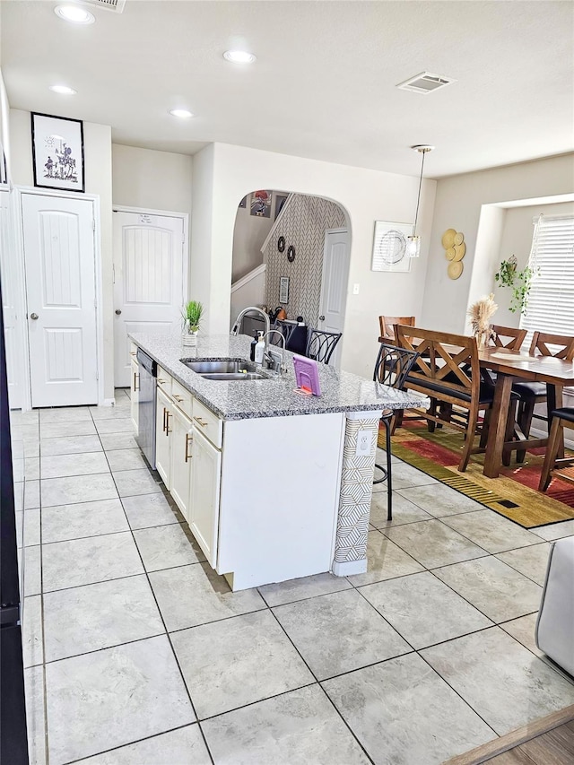 3519 Rossini Dr, Katy, TX 77493 - kitchen featuring a sink, arched walkways, dishwasher, white cabinetry, and light stone counters