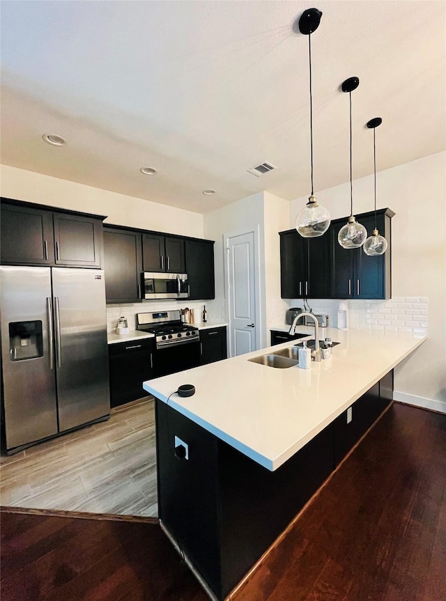 1840 Parana Dr, Houston, TX 77080 - kitchen featuring appliances with stainless steel finishes, a sink, dark cabinetry, light wood finished floors, and recessed lighting