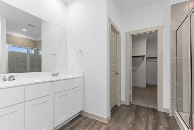 407 Emma St, Angleton, TX 77515 - bathroom featuring a shower stall, wood finished floors, double vanity, baseboards, and a walk in closet