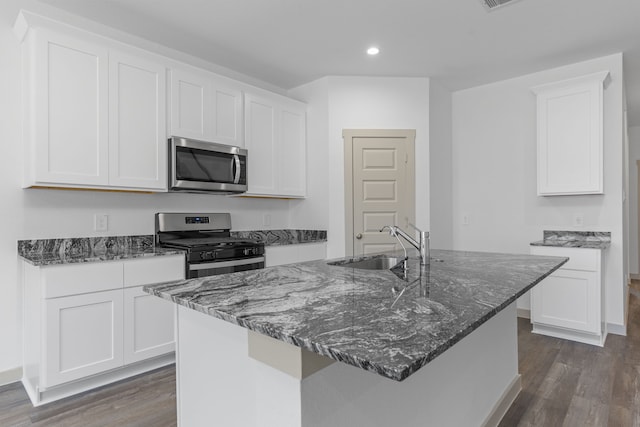 407 Emma St, Angleton, TX 77515 - kitchen featuring appliances with stainless steel finishes, a sink, dark wood-style flooring, recessed lighting, and dark stone countertops