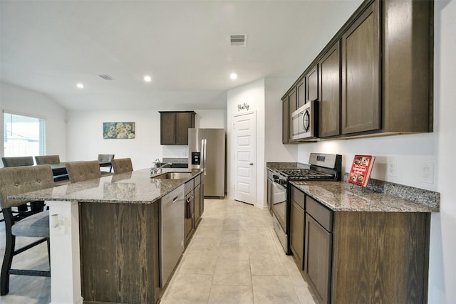 1023 Cattle Chute Ct, Rosharon, TX 77583 - kitchen featuring stainless steel appliances, a kitchen bar, dark stone countertops, dark brown cabinets, and a sink
