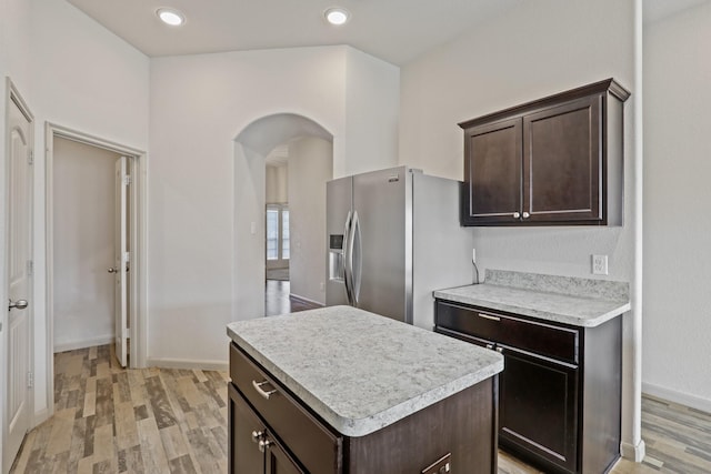 5207 Corbridge Glen Ct, Katy, TX 77449 - kitchen with stainless steel refrigerator with ice dispenser, arched walkways, light wood-style floors, dark brown cabinetry, and recessed lighting