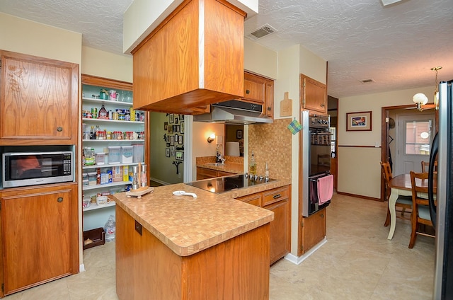12023 Scottsdale Dr, Meadows Place, TX 77477 - kitchen featuring black appliances, a textured ceiling, a warming drawer, brown cabinetry, and a peninsula