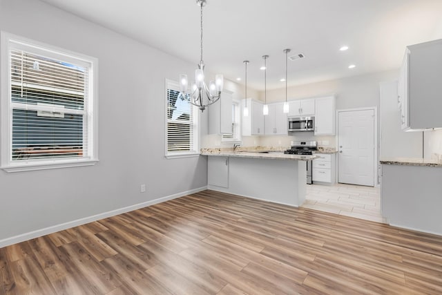 1505 Hussion St, Houston, TX 77003 - kitchen with stainless steel appliances, a peninsula, light wood finished floors, a chandelier, and white cabinetry