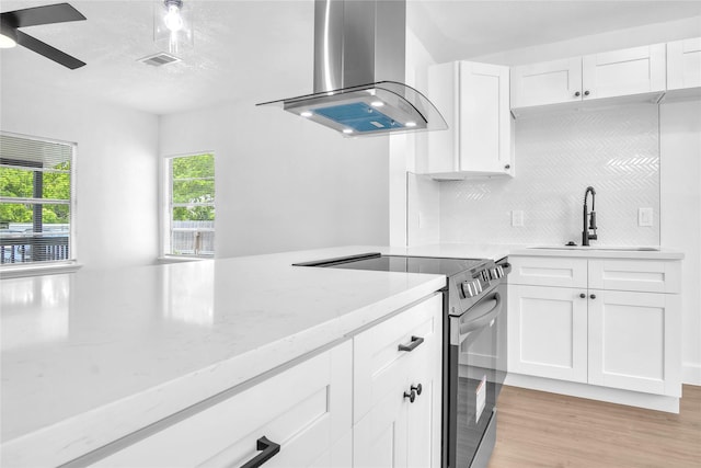 607 Rosedale St, La Marque, TX 77568 - kitchen featuring stainless steel electric range oven, wall chimney range hood, a sink, ceiling fan, and decorative backsplash