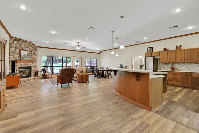 210 Harbor Run Dr, Coldspring, TX 77331 - kitchen featuring open floor plan, ornamental molding, light countertops, brown cabinets, and a stone fireplace